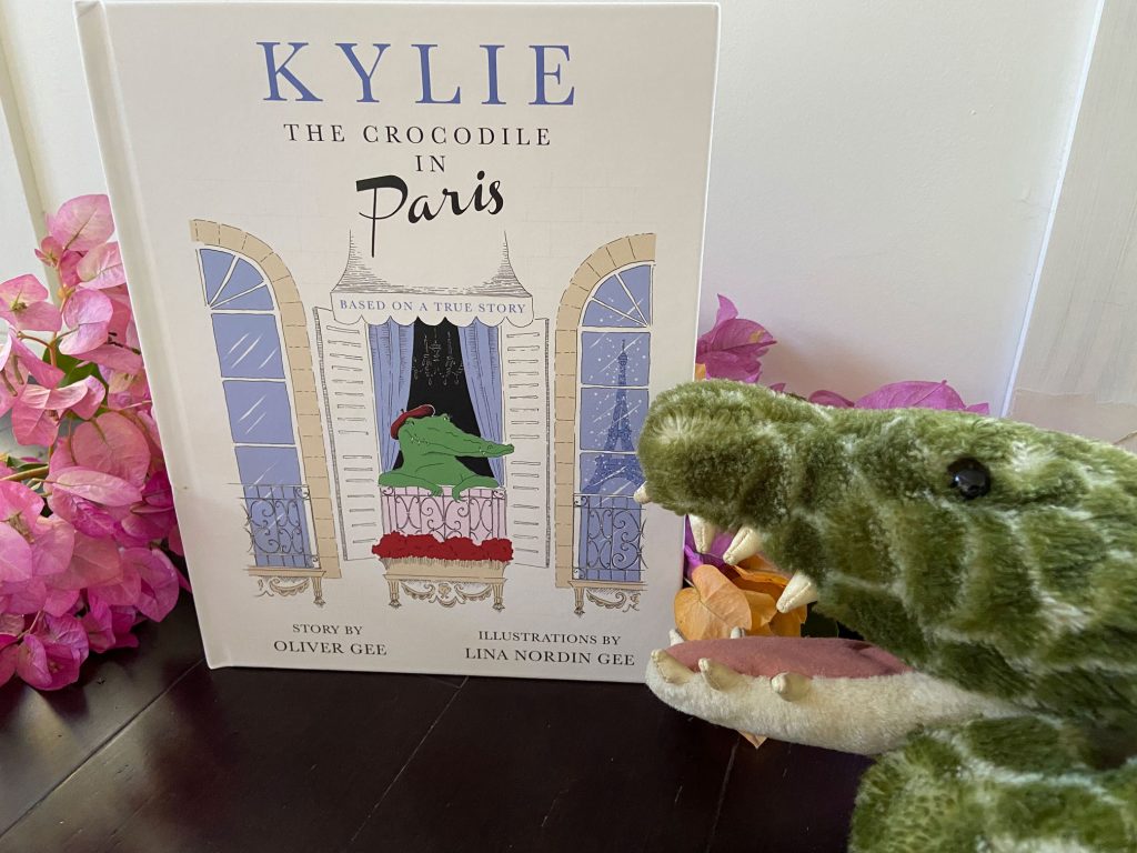 Book Kylie the Crocodile surrounded by bougainvillea and a plush crocodile